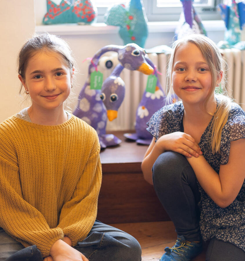 Zwei Mädchen stehen vor ihren Kunstwerken