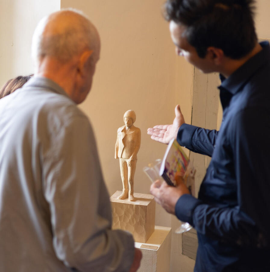 Der Künstler Sinan Al-Shakirche erläutert einem Besucher sein Kunstwerk und weist mit der Hand dorthin